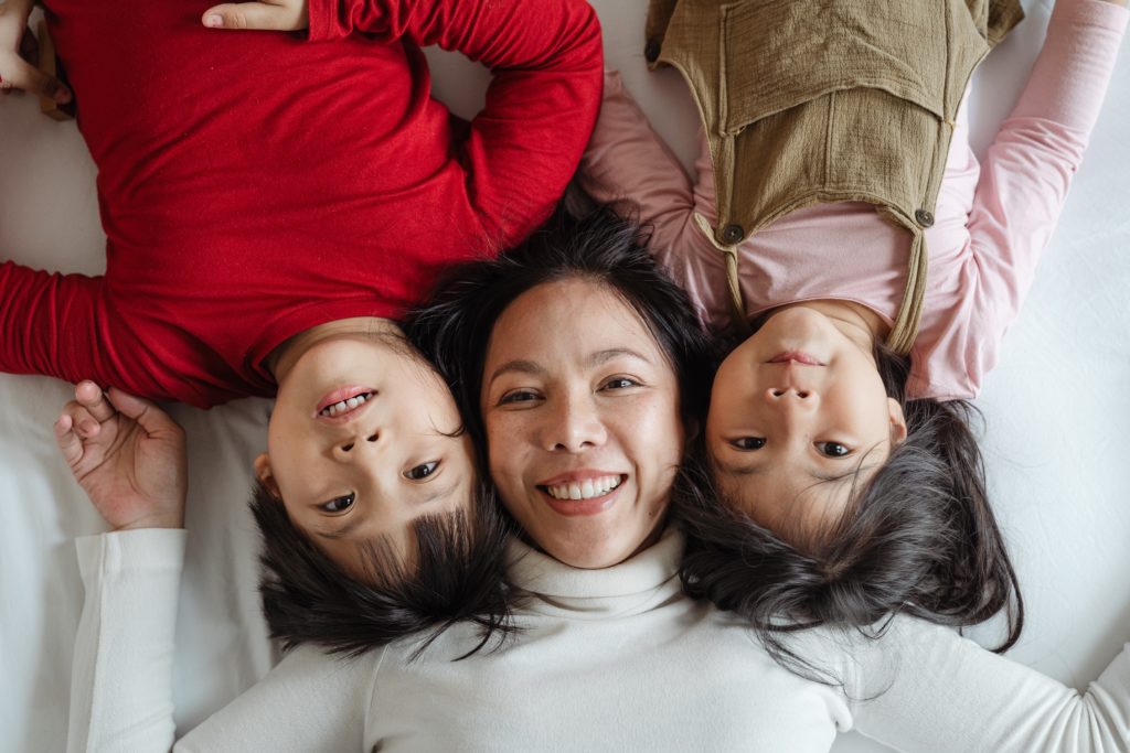 mère avec ses 2 enfants allongés sur un lit