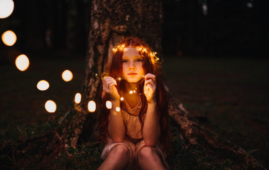 petite fille tenant une guirlande de lumière