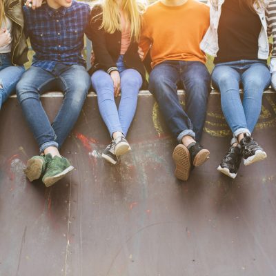Summer holidays and teenage concept – group of smiling teenagers with skateboard hanging out outside. adolescents assis sur un mur
