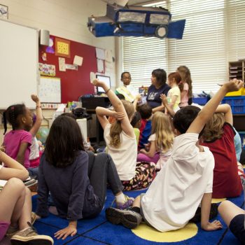 des enfants assis par terre sur des tapis en classe