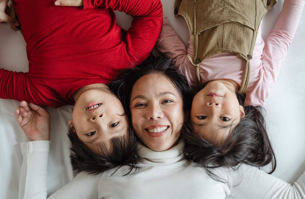 mère avec ses 2 enfants allongés sur un lit
